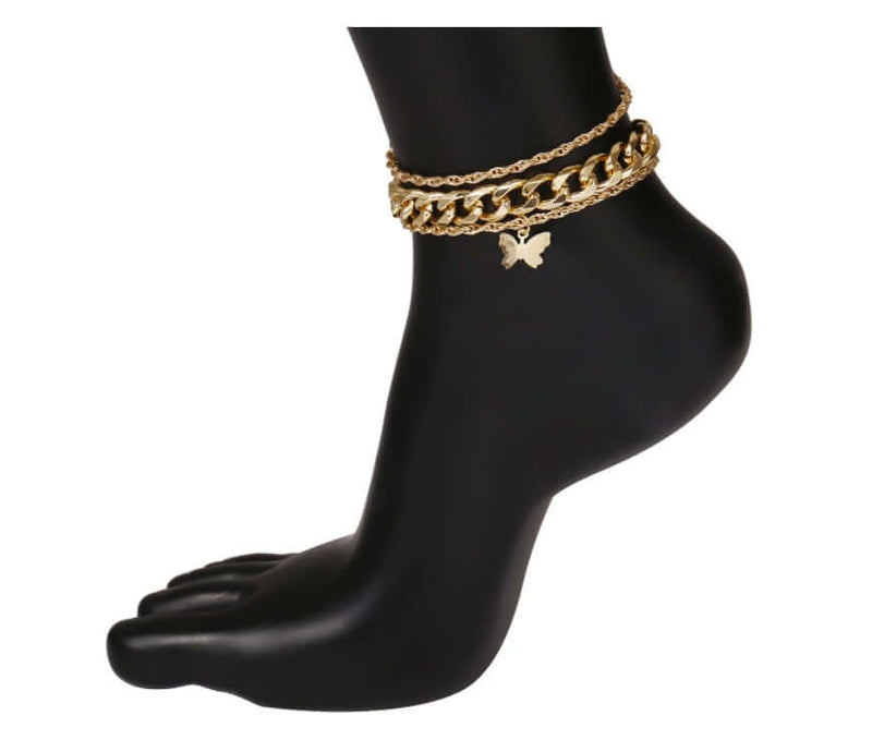 Gold anklets on a black foot mannequin against a white background