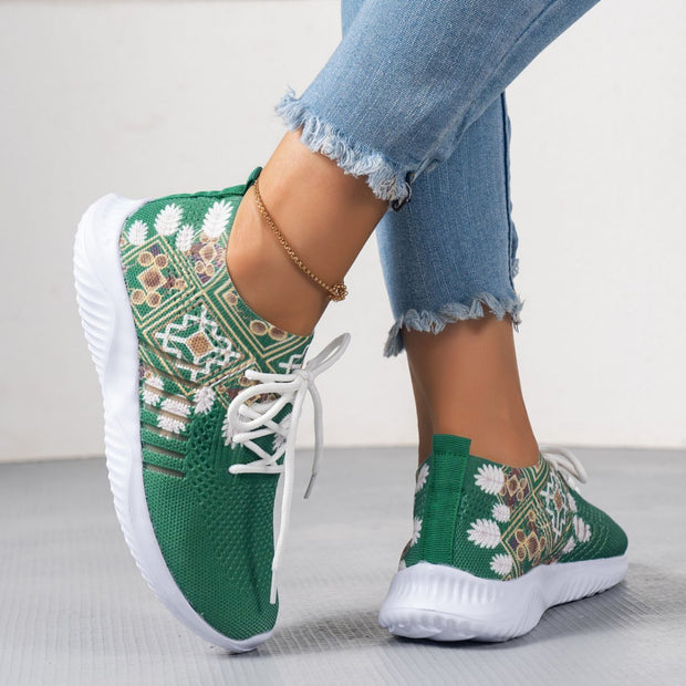 Green sneakers with white patterns worn by a person on a light background