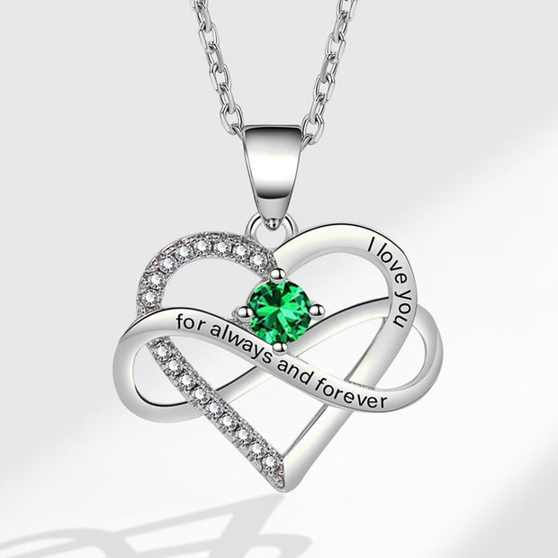 Heart-shaped silver pendant with green gemstone and 'I love you' engraving on a white background
