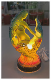 Colorful mermaid-shaped lamp on a white surface with a blurred background