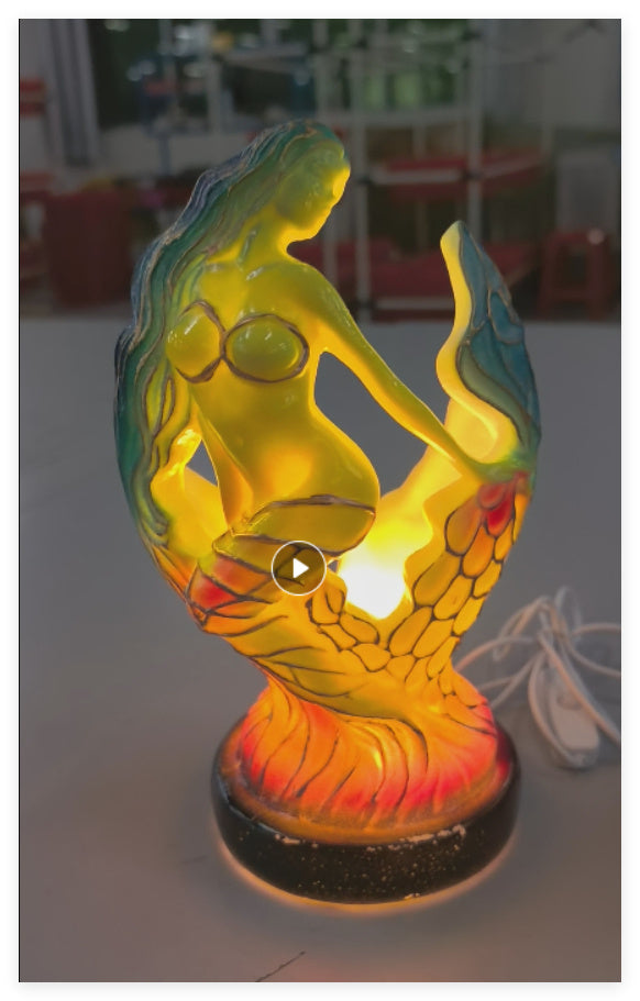 Colorful mermaid-shaped lamp on a white surface with a blurred background