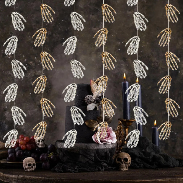 Decorative garland with skeleton hands hanging above a table with candles and fruit.
