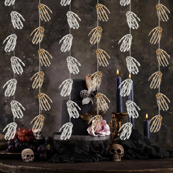 Decorative garland with skeleton hands hanging above a table with candles and fruit