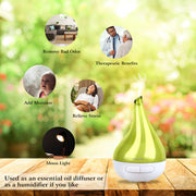 Green essential oil diffuser on a wooden surface with therapeutic benefits text and blurred outdoor background.