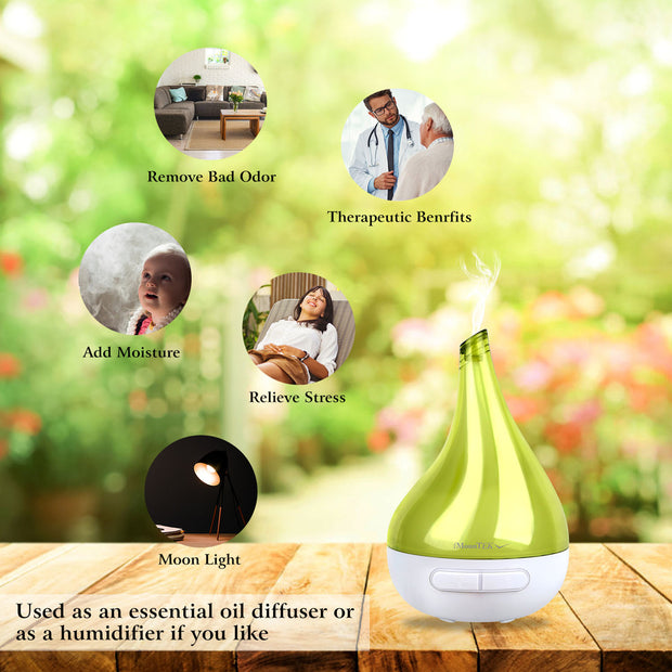 Green essential oil diffuser on a wooden surface with therapeutic benefits text and blurred outdoor background.