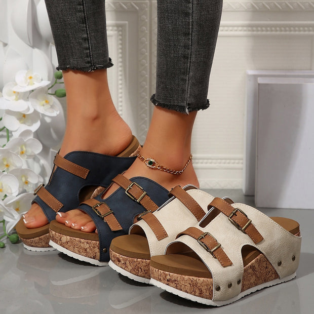 Two pairs of sandals, one navy and one beige, worn on feet with a neutral background.