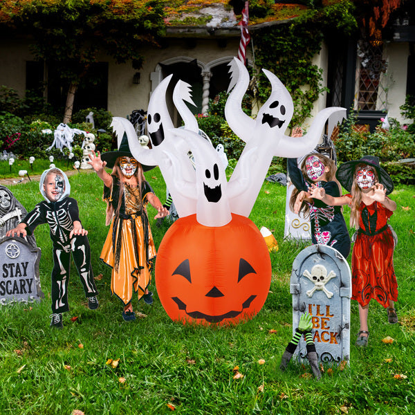 Children in Halloween costumes with inflatable ghost and pumpkin in a decorated yard.