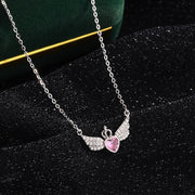 Necklace with a pink heart and angel wing pendant on a dark background
