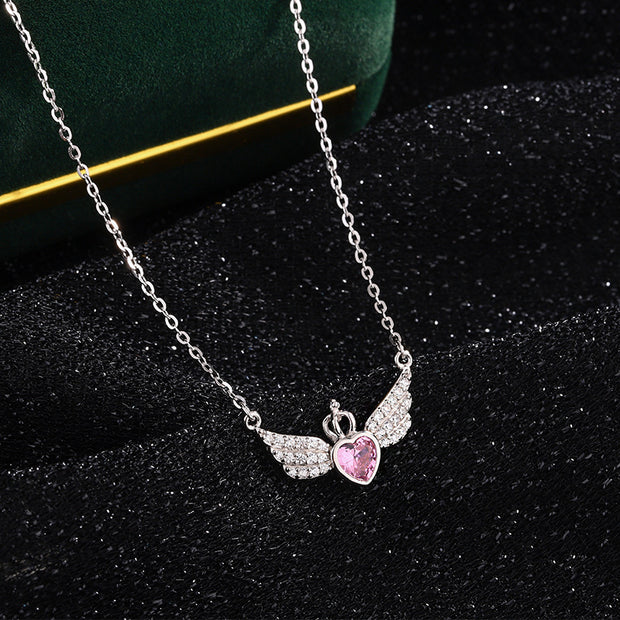 Necklace with a pink heart and angel wing pendant on a dark background