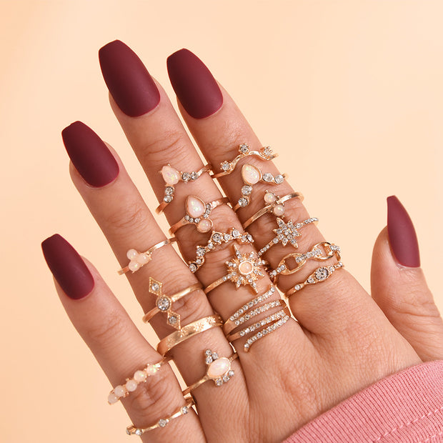 Hand wearing multiple gold rings with a plain background