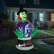 Halloween inflatable decoration of a witch with a purple dress and green hair in a yard.