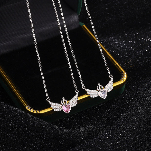 Two silver necklaces with heart and wing designs on a black background