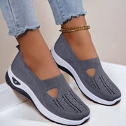 Gray slip-on shoes with white soles worn with light blue jeans on a neutral background