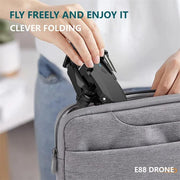 Person placing a drone into a gray suitcase with text 'Fly Freely and Enjoy It' and 'E88 Drone'.