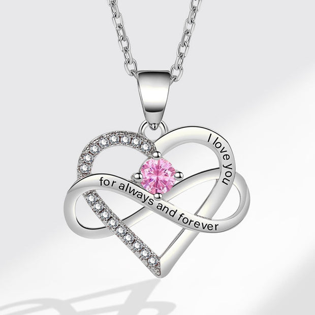 Heart-shaped silver necklace with pink gemstone and 'I love you' engraving on a white background