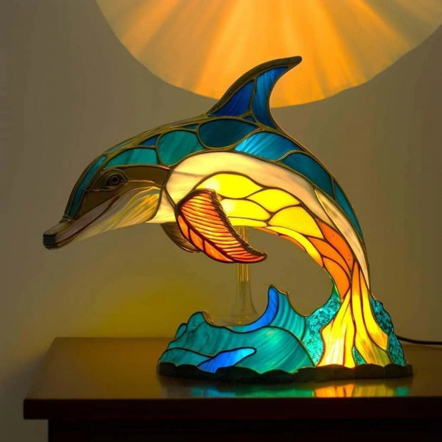 Stained glass dolphin lamp on a wooden surface with a warm glow.