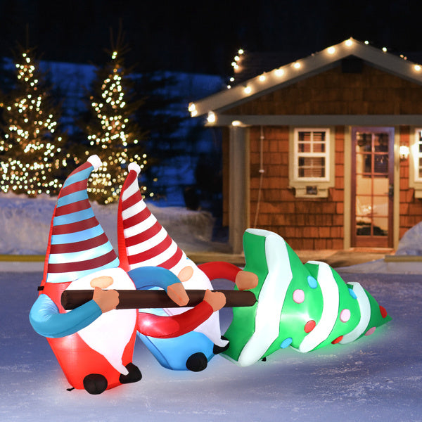 Inflatable gnomes and Christmas tree with a cabin and trees in the background