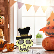 Decorative skull with a top hat on a table with pumpkins and a bunting in the background