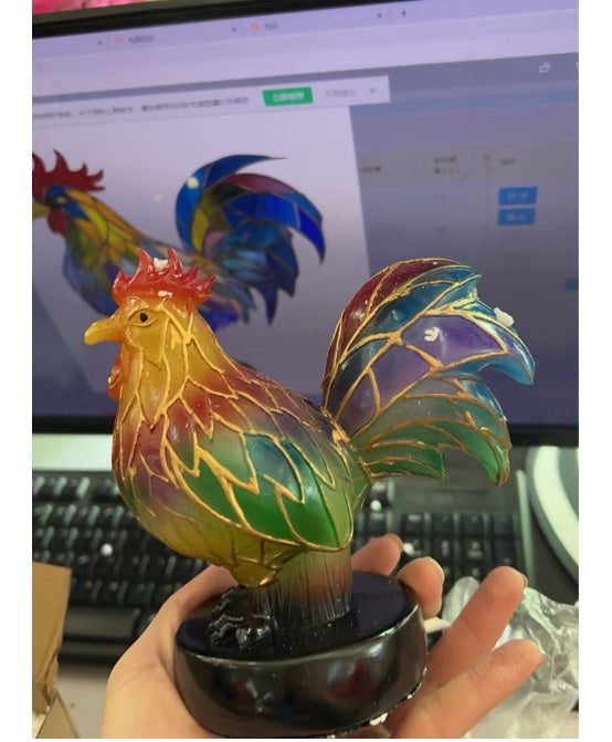 Colorful rooster figurine held in front of a computer screen
