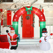 Inflatable Christmas arch with Santa Claus and snowman decorations in front of a red door.