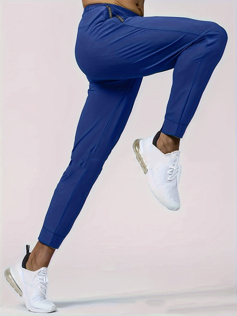 Person wearing blue jogger pants and white sneakers on a light pink background