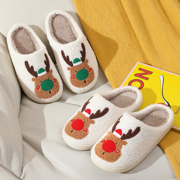 Pair of white slippers with reindeer design on a light background