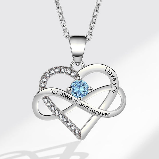 Silver heart-shaped necklace with blue gemstone and 'I love you' engraving on a light gray background