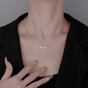 Necklace with a delicate pendant worn by a person against a neutral background