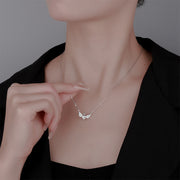Necklace with a delicate pendant being adjusted on a person wearing a black top.
