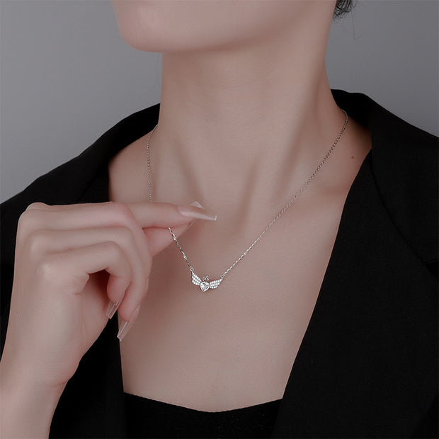 Necklace with a delicate pendant being adjusted on a person wearing a black top.