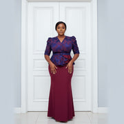 Woman wearing a blue and red outfit with a matching skirt, standing in front of a door.