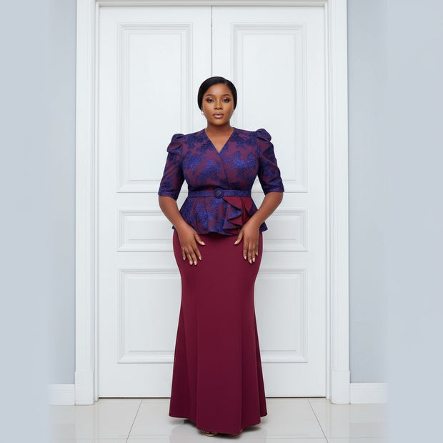 Woman wearing a blue and red outfit with a matching skirt, standing in front of a door.