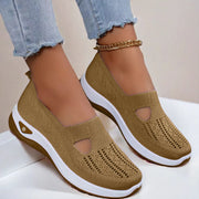 Brown slip-on shoes with white soles worn by a person on a light background