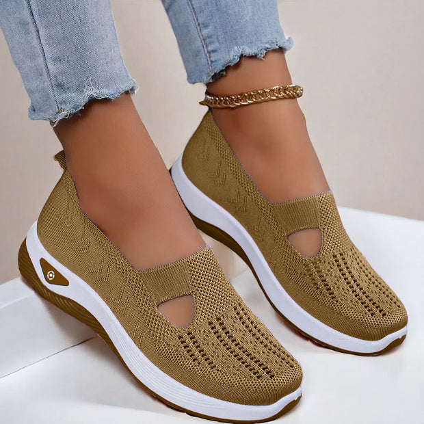 Brown slip-on shoes with white soles worn by a person on a light background