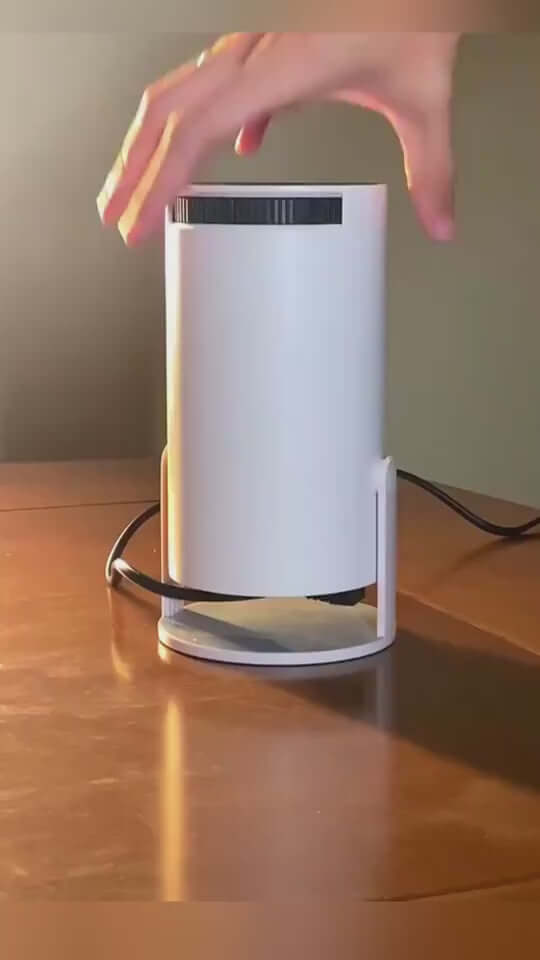 White portable projector being adjusted on a wooden surface, showcasing its sleek design and compact size.
